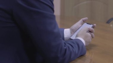 Bir adam cep telefonuyla masada oturuyor.