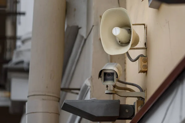 Cctv and loudspeaker. outdoor surveillance and tracking security camera with a megaphone on the wall of building. — Stock Photo, Image
