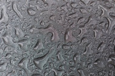 Su geçirmez bir yüzeye su damlıyor. Bir arabanın üzerine su damlası. Metal üzerindeki damlalardan oluşan gümüş arkaplan