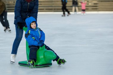 Çocuk paten sahasında kayıyor. Çocuk, ailesiyle birlikte buz pateni öğreniyor..
