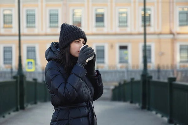 Dívka se sklenicí kávy na ulici. Hřejivě oblečený a usmívající se — Stock fotografie