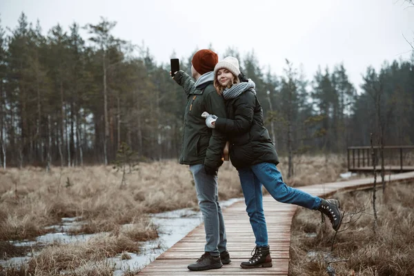 Una chica y un chico haciendo una selfie en la naturaleza . — Foto de Stock