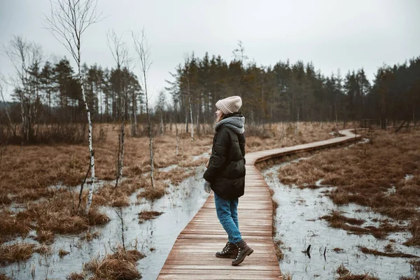 Девушка идет по лесному болоту в шляпе и куртке — стоковое фото