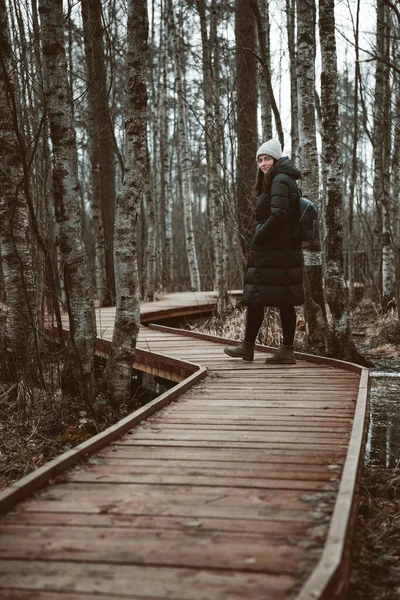 Mädchen im Mantel, das im Wald spazieren geht. Herbst, kaltes Wetter im Sumpf. — Stockfoto