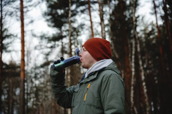 Ein Mann trinkt aus Thermoskannen in der Natur. — Stockfoto