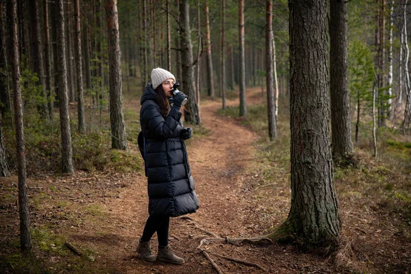 Kız ormanda yürüyor ve termostan içiyor. — Stok fotoğraf