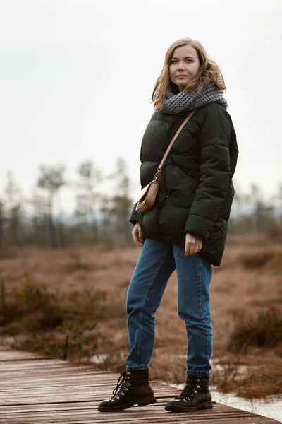 Ragazza in cappotto passeggiando nel bosco. autunno, freddo nella palude . — Foto Stock