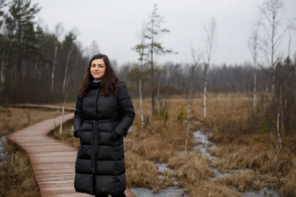 Dívka v kabátě procházející se lesem. podzim, chladné počasí v bažině. — Stock fotografie