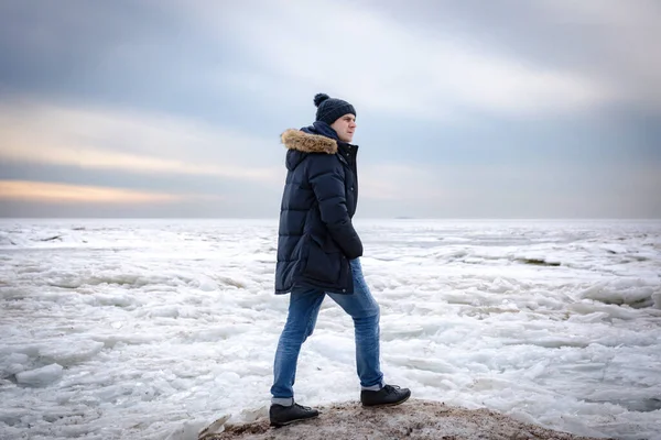 Portrét muže na jezeře v zimě. Chlápek v klobouku a bundě proti ledu — Stock fotografie
