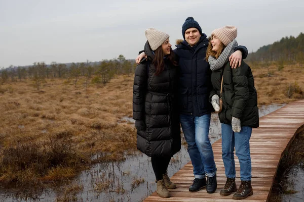 Egy fiú és két lány sétál a természetben. A barátok nevetnek és mosolyognak — Stock Fotó