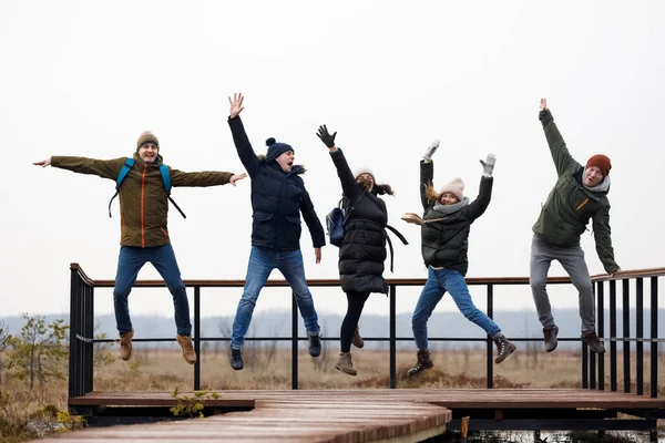 Five people jump. company of friends relaxes in nature