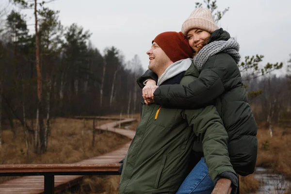 Pareja en un paseo por el bosque. Chica y novio caminan en la naturaleza en chaquetas y sombreros . —  Fotos de Stock