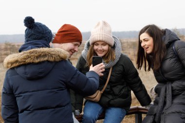 Açık havada ayrı ayrı mesajlaşıyoruz. Her biri 5 arkadaşından oluşan bir şirket telefonuna bakıyor.