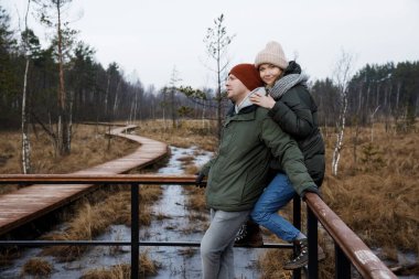 Ormanda yürüyüşe çıkmış bir çift. Kız ve erkek arkadaş doğada ceket ve şapkalarla dolaşır..