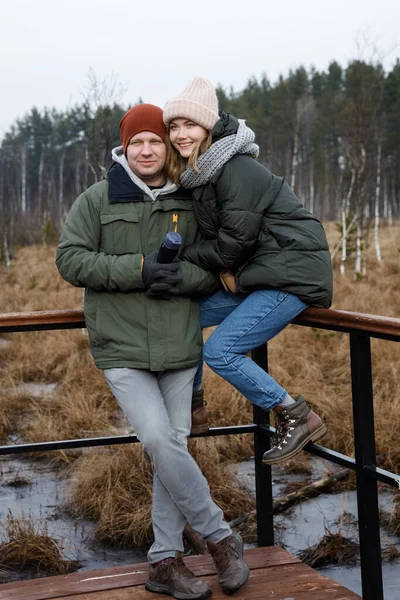 Egy pár sétálni az erdőben. Lány és barát a természetben sétálnak zakóban és kalapban.. — Stock Fotó