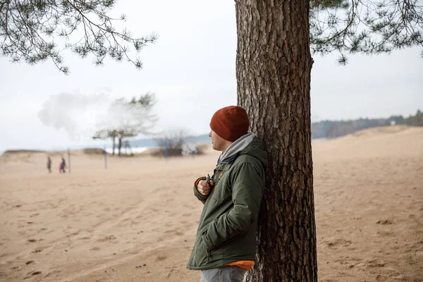 Portrét chlapa v bundě a čepice u stromu — Stock fotografie