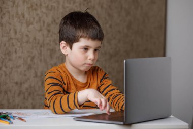 Küçük bir çocuk bilgisayarda çalışıyor. Ev karantinasında uzaktan öğrenim