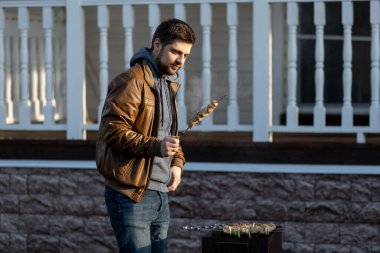 Elde şiş kebap. Bir adam sokakta kömür pişirir.