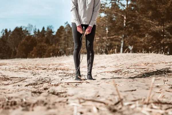 Девушка занимается спортом на природе. Упражнения с веревкой, песком и озером . — стоковое фото