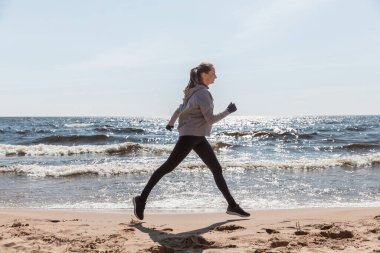 Kız plajda koşar, atletin silueti