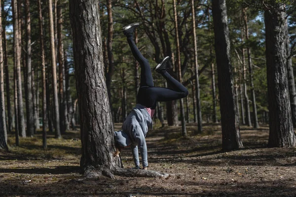 Στέκεται στα χέρια της, ένα κορίτσι στη φύση ασχολείται με τον αθλητισμό. Δάσος πεύκου αντί για γυμναστήριο — Φωτογραφία Αρχείου