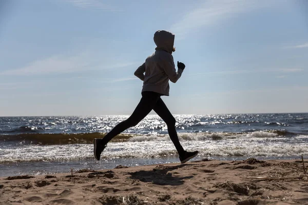 Menina corre na praia, a silhueta do atleta — Fotografia de Stock
