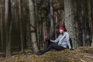 Kız spordan sonra dinleniyor. Sporcu, egzersizden sonra dambıllarla su içer.. 