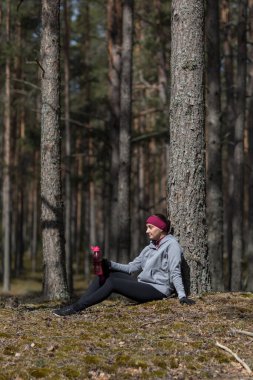 Ormandaki kız koşudan sonra su içiyor.