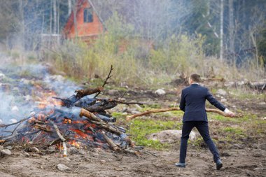 Finansal kriz. İş adamı mesleğini değiştirir. Ceketli adam çöpü yakıyor.