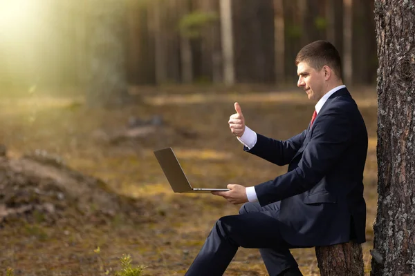 Videoconferencia de un hombre de negocios en una calle fuera de la ciudad en la naturaleza. Empresario en un video chat en el parque . — Foto de Stock