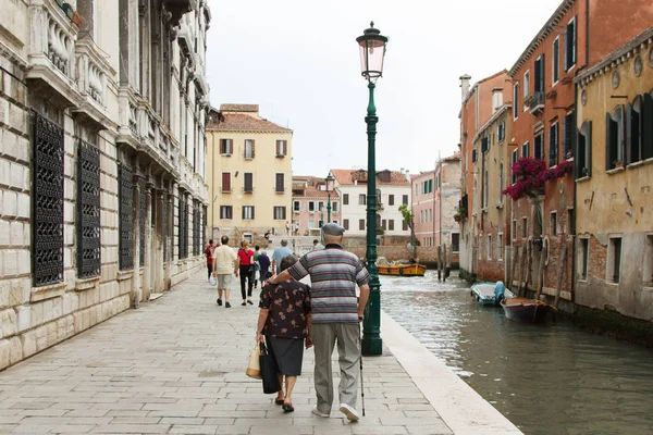 Elderly couple walking arm in arm through the ancient streets of