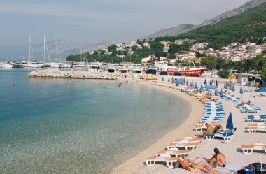Tatilcilerin sahilde vakit, güneşlenmek ve yüzmek.