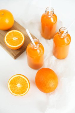 Beyaz bir arka plan üzerinde masada üç şişe portakal suyu ve tüpler vardır