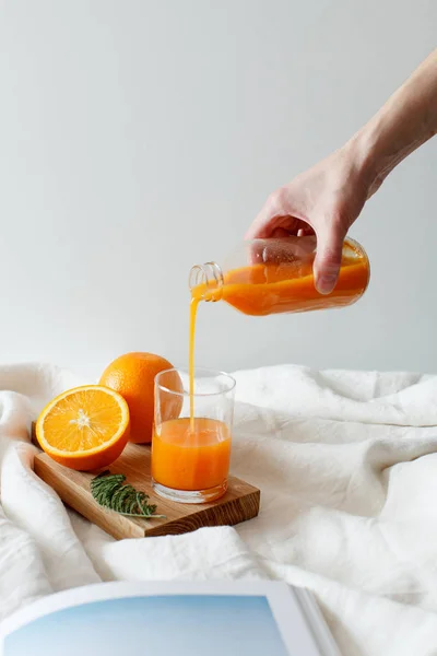 Kız bir portakal bir şişeden taze bir cam içine dökülen. Ahşap tahta ve dergi bir portakal bulursun. 