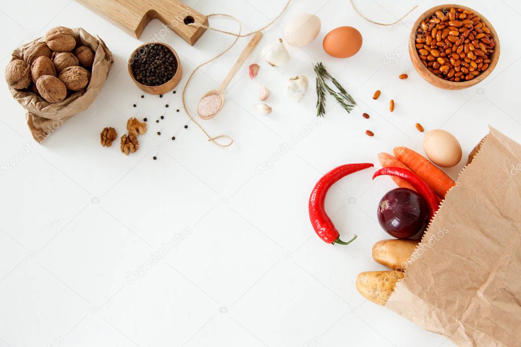 Vegetables, nuts, beans, potatoes, red peppers, chicken eggs, other food and kitchen appliances lie on a white background.