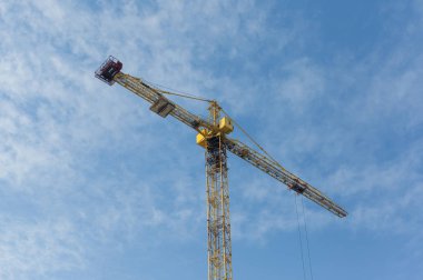 Mavi gökyüzü arka plan üzerinde sarı inşaat vinç. Güneşli bir gün, hor