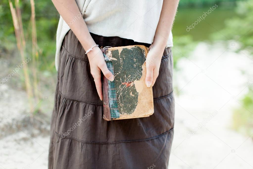 A young girl is holding a very old shabby book in her hands. Sum