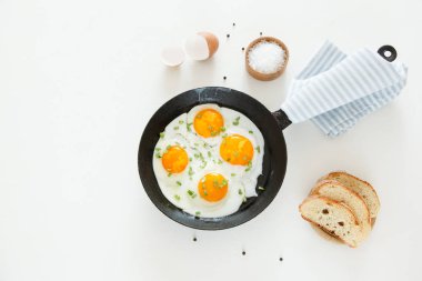 Bir tavada kızarmış yumurta ekmek ve beyaz bir arka plan üzerine tuz.