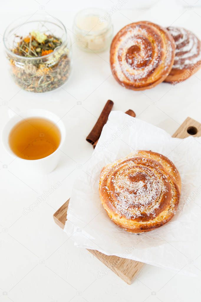 Herbal tea and sweet buns with sugar and cinnamon on a white background.