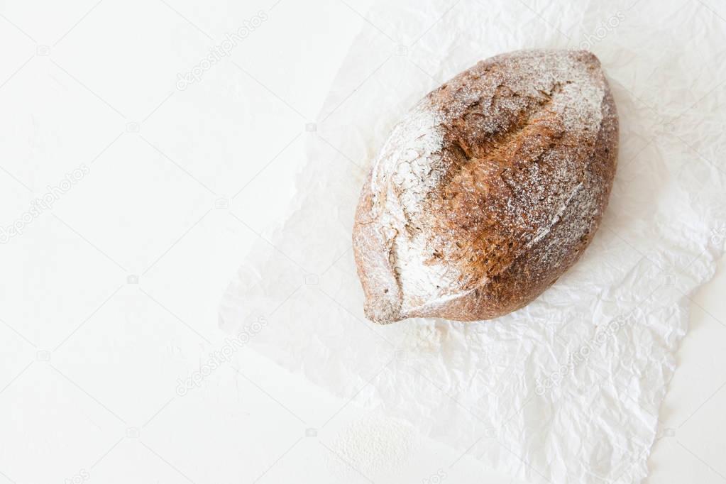 A loaf of homemade bread in a paper on a white background with space for your text.