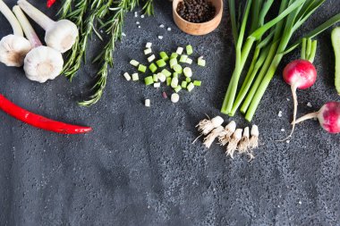 Turp, biberiye, biber biber ve karanlık bir arka plan üzerinde lahana ile genç yeşil sarımsak.