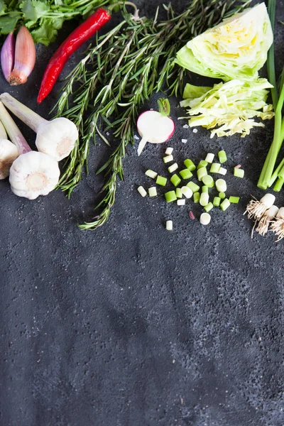 Turp, biberiye, biber biber ve karanlık bir arka plan üzerinde lahana ile genç yeşil sarımsak.