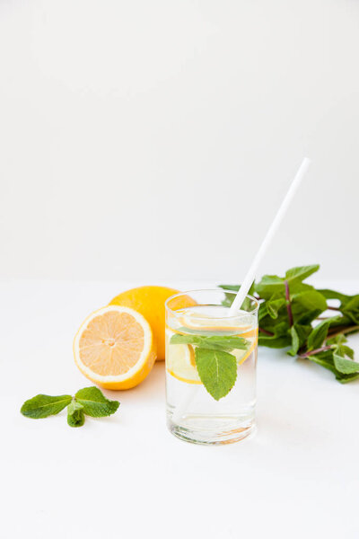 Homemade lemonade with water, lemon and mint leaves in a glass on a white background.