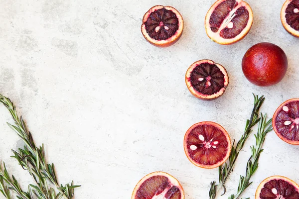 Naranja siciliano rojo entero y cortado sobre un fondo claro con ramas de romero. Luz del día, espacio abierto para su texto . — Foto de Stock