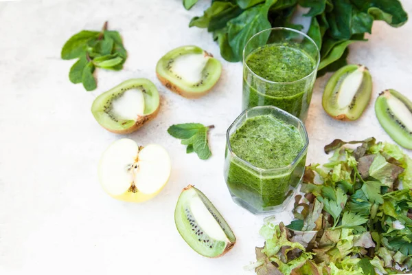 Cóctel verde en una botella y en un vaso con espinacas, menta, romero, kiwi y manzana sobre un fondo claro . —  Fotos de Stock