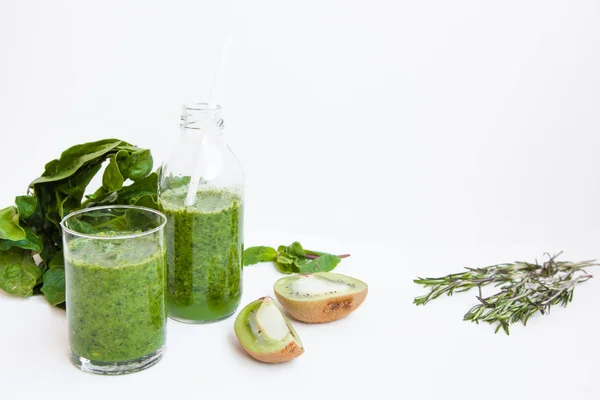 Cóctel verde en una botella y en un vaso con espinacas, menta, romero, kiwi y manzana sobre un fondo claro . —  Fotos de Stock