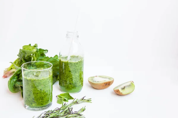 Зеленый коктейль в бутылке и в стакане со шпинатом, мятой, кемари, киви и яблоком на светлом фоне . — стоковое фото