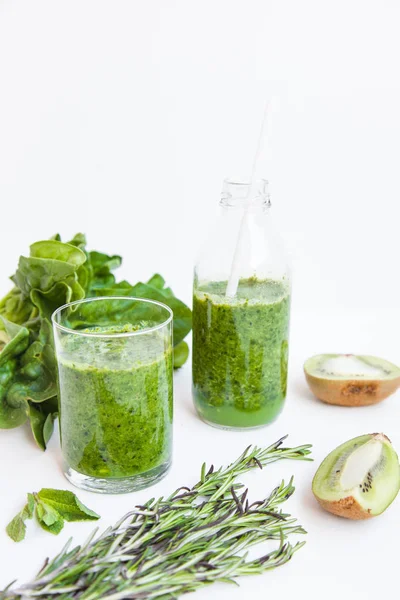 Cóctel verde en una botella y en un vaso con espinacas, menta, romero, kiwi y manzana sobre un fondo claro . —  Fotos de Stock