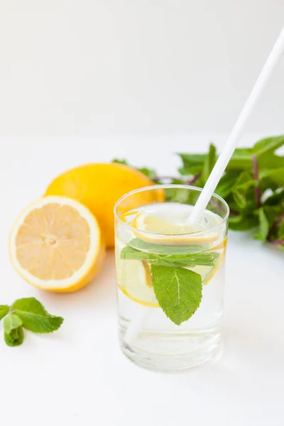 Limonada casera con agua, limón y hojas de menta en un vaso sobre un fondo blanco . —  Fotos de Stock