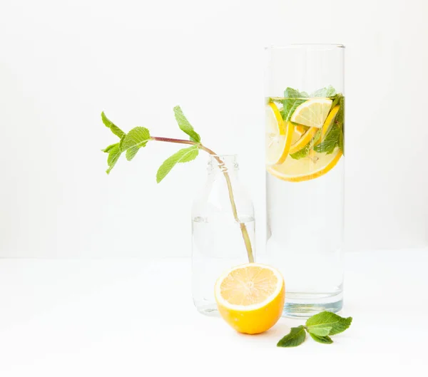 Limonada casera con agua, limón y hojas de menta en un vaso sobre un fondo blanco . —  Fotos de Stock